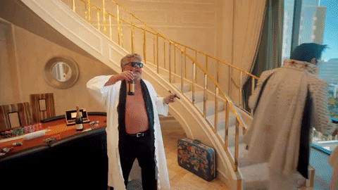 Man in a robe drinking and celebrating on a lavish staircase meme